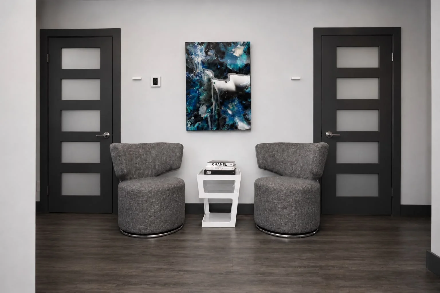 Waiting nook with grey swivel armchairs and a blue artwork