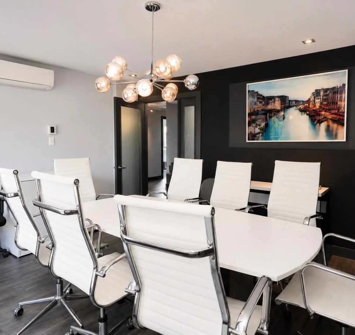 Meeting room with white chairs, artwork and designer lighting