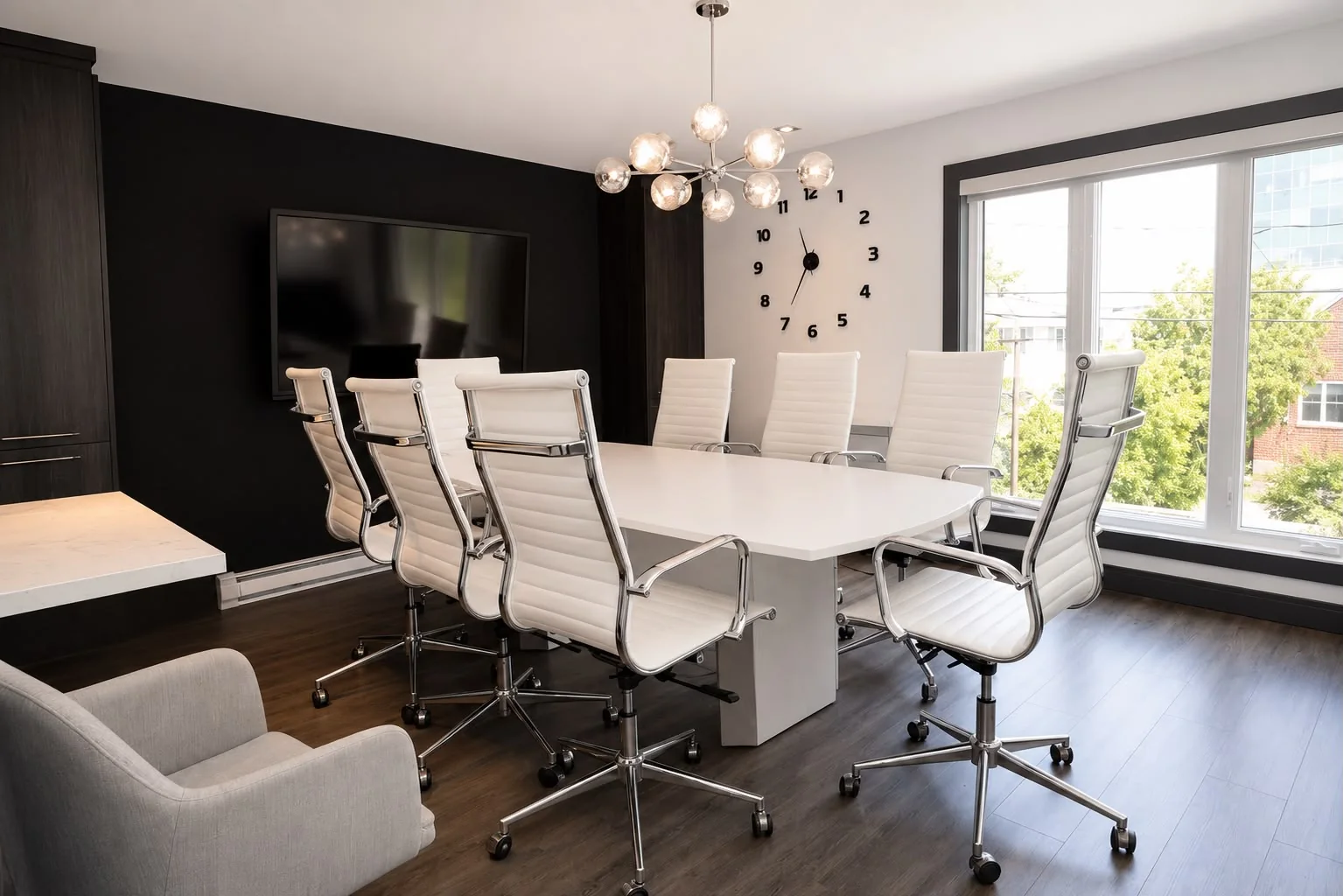 Conference room with a large white table, screen and globe chandelier
