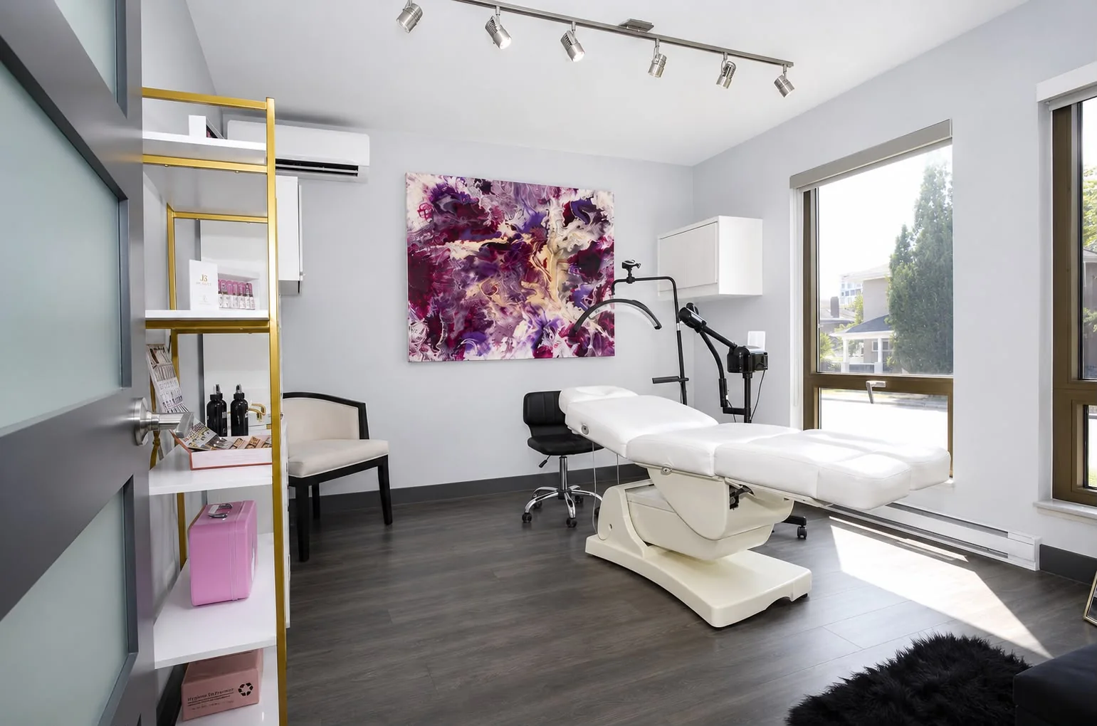 Cabine de soins du visage avec table de traitement, lampe loupe et grande toile d'art
